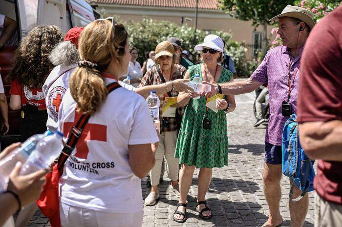 Freiwillige Helfer des Roten Kreuzes versorgen die Menschen mit Wasser