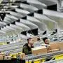 Men work at a distribution station in the 855,000-square-foot Amazon fulfillment center in Staten Island, one of the five boroughs of New York City, on February 5, 2019. - Inside a huge warehouse on Staten Island thousands of robots are busy distributing thousands of items sold by the giant of online sales, Amazon. (Photo by Johannes EISELE / AFP)