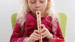 Mädchen sitzt hinter Adventskranz und spielt Flöte - Advent celebration, sujet advent, musizieren, blockflöte