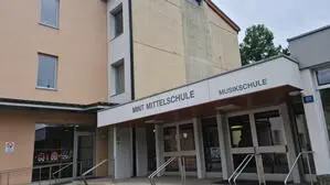 Man sieht ein Gebäude, auf dem „Mittelschule“ und „Musikschule“ steht