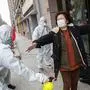 A woman (R), who has recovered from the COVID-19 coronavirus infection, is disinfected by volunteers as she arrives at a hotel for a 14-day quarantine after being discharged from a hospital in Wuhan, in China's central Hubei province on March 1, 2020. - China on March 1 reported 35 more deaths from the new coronavirus, taking the toll in the country to 2,870. (Photo by STR / AFP) / China OUT