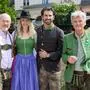 Vier Personen in Tracht, drei Männer und eine Frau, lachen in die Kamera.