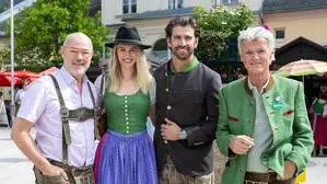 Vier Personen in Tracht, drei Männer und eine Frau, lachen in die Kamera.