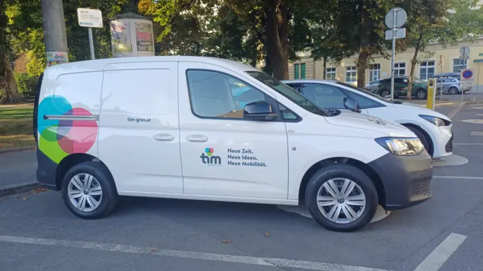ein weißer VW-Caddy mit buntem Tim-Logo auf einem Tim-Parkplatz