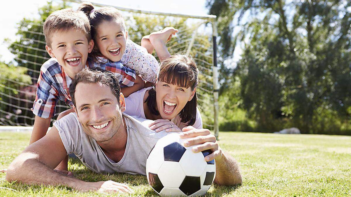 Family Playing Football In Garden Together