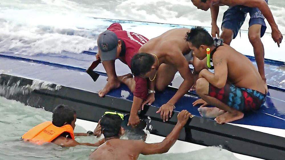 Retter schlagen ein Loch in das Boot, um eine Frau zu retten