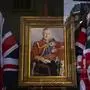 An employee arranges a shop window decorated with a painting of King Charles III in London, Thursday, May 4, 2023. The Coronation of King Charles III will take place at Westminster Abbey on May 6. (AP Photo/Emilio Morenatti)