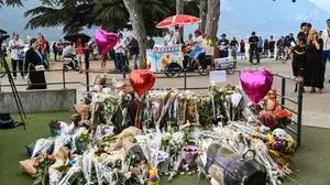 This photograph taken on June 9, 2023, shows flowers, candles and balloons laid in the 'Jardins de l'Europe' parc in Annecy, French Alps, for the victims of a stabbing attack that occured the day before. A man armed with a knife stabbed four preschool children and injured two adults by a lake in the French Alps on June 8, 2023 in an attack that sent shock waves through the country. The suspect is a Syrian in his early 30s who was granted refugee status in Sweden in April, a police source told AFP. He was arrested at the scene. (Photo by OLIVIER CHASSIGNOLE / AFP)