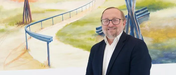 Hannes Stickler vor einem Wandgemälde von Gerhard Kubassa im Wartebereich der PVE Kindberg