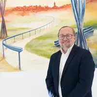 Hannes Stickler vor einem Wandgemälde von Gerhard Kubassa im Wartebereich der PVE Kindberg