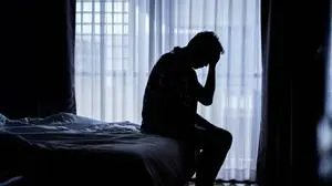 Lonely man silhouette sitting on the bed feeling depressed and stressed in the dark bedroom, Depression and anxiety disorder concept