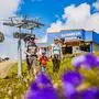 Eine Frau, ein Mann und ein Kleinkind wandert, im Hintergund ist eine Bergbahn
