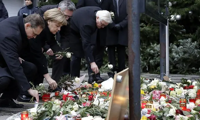 From left, the Mayor of Berlin Michael Mueller, German Chancellor Angela Merkel, German Interior Minister Thomas de Maiziere and German Foreign Minister Frank-Walter Steinmeier attend a flower ceremony at the Kaiser-Wilhelm-Gedaechniskirche in Berlin, Germany, Tuesday, Dec. 20, 2016 the day after a truck ran into a crowded Christmas market and killed several people. (AP Photo/Michael Sohn)