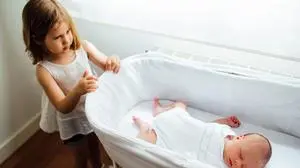 Older sister and little newborn brother in the crib. Managing jealousy between siblings