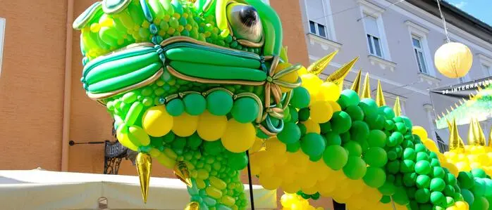 Ein aus Luftballons geflochtener, riesiger Leguan schwebt durch die Innenstadt von Lienz