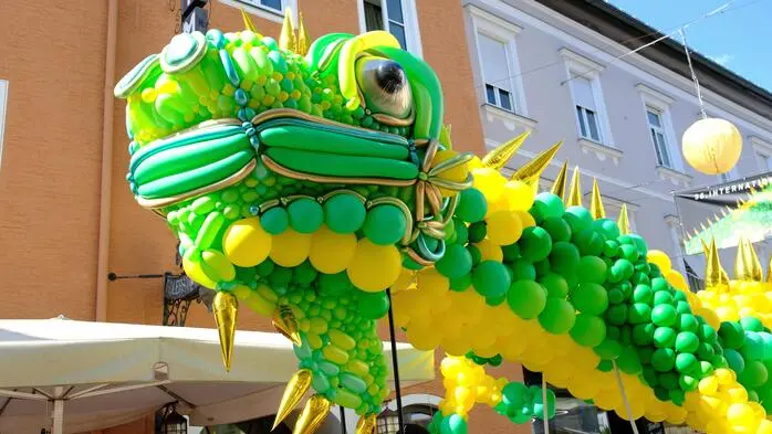 Ein aus Luftballons geflochtener, riesiger Leguan schwebt durch die Innenstadt von Lienz