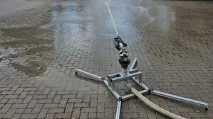 Ein Weitstrahlregner der Firma Komet steht auf dem Firmengelände und versprüht Wasser