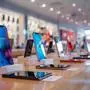 A range of new, modern smartphones showcased on stands against a store with colorful backgrounds and soft lighting.