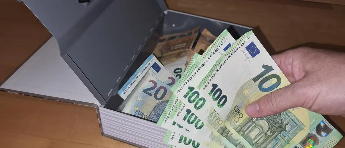 Jemand stiehlt Geld aus einer Handkassa