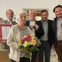 Eine ältere Frau hält einen großen Blumenstrauß - dahinter stehen vier Gemeindevertreter | Friederike Pucher erhielt das Goldene Ehrenabzeichen der Marktgemeinde Lavamünd