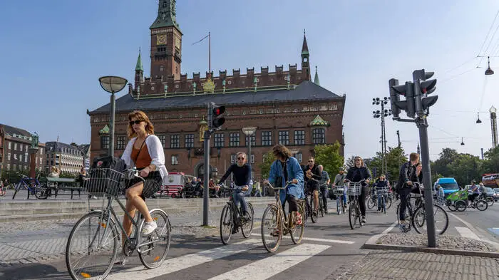 Eine Gruppe von Radfahrerinnen und Radfahrern fährt durch die Innenstadt von Kopenhagen.  | 56 Prozent der Bevölkerung Kopenhagens fahren täglich mit dem Fahrrad