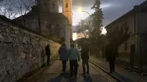 Blick auf eine dunkle Straße, in der Mitte des Bildes sieht man einen beleuchteten Kirchturm