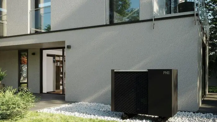 Das Bild zeigt eine Wärmepumpe vor einem modernen Haus mit hellgrauen Außenfassaden