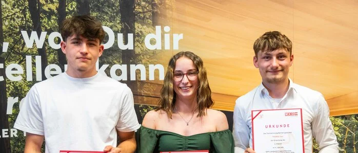 Drei junge Personen halten Urkunden