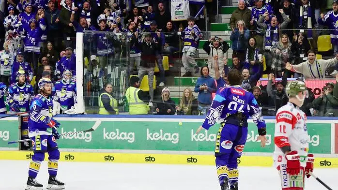 Blick auf zwei Eishockeyspieler auf dem Eis, dahinter erhebt sich die Zuschauertribüne.