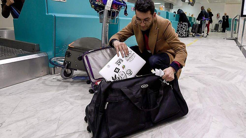 Ein Passagier in Tunesien, der seinen Laptop umpacken muss