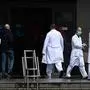 Health workers stand outside La Paz hospital in Madrid on March 23, 2020 amid a national lockdown to fight the spread of the COVID-19 coronavirus. - The coronavirus death toll in Spain surged to 2,182 after 462 people died within 24 hours, the health ministry said. (Photo by PIERRE-PHILIPPE MARCOU / AFP)