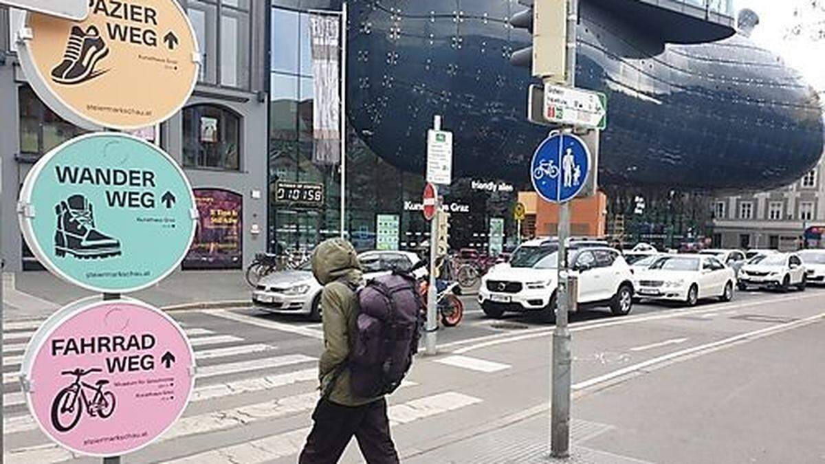 Drei bunte Hinweistafeln vor dem Grazer Kunsthaus