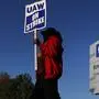 FILE - In this Oct. 9, 2019, file photo, Yolanda Jacobs, a United Auto Workers member, walks the picket line at the General Motors Romulus Powertrain plant in Romulus, Mich.  The United Auto Workers and General Motors have reached a tentative contract agreement that could end a monthlong strike that brought the automaker's U.S. factories to a standstill. The deal was hammered out Wednesday, Oct. 16, but it won't immediately end the strike by more than 49,000 workers. (AP Photo/Paul Sancya, File)
