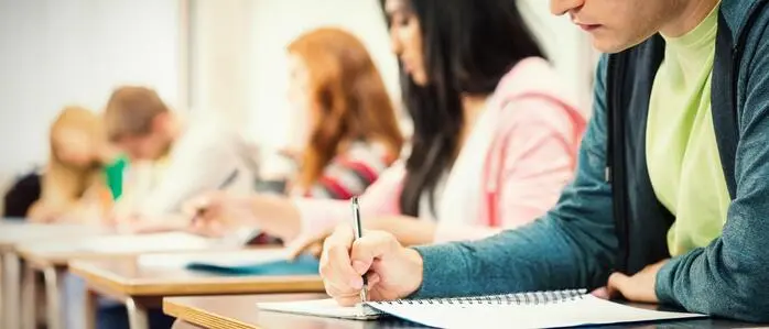 Mehrere Schüler sitzen in einer Klasse und schreiben an einer Klausur