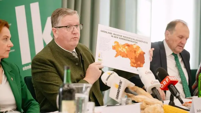 Ein Mann hält eine Grafik in den Händen, auf der das Bundesland Steiermark aufgezeichnet ist. In jeder Region ist eine unterschiedliche Farbe. Sie kennzeichnet jeweils, wie viel Regen in den Regionen gefallen ist