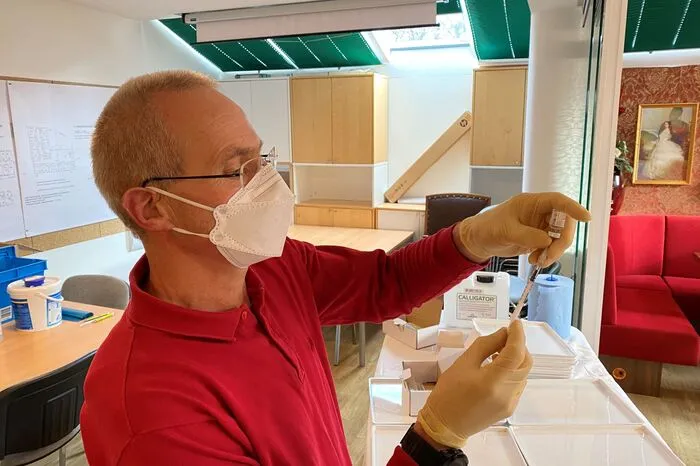 Hausarzt Kurt Sternad bereitet die Covid-Impflösung vor und injiziert sie den Bewohner, daraufhin wird kontrolliert ihren Gesundheitszustand, um etwaige Nebenwirkungen auszuschließen