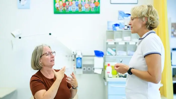Eine Patientin und eine Ärztin unterhalten sich in einer Arztpraxis in der Gebärdensprache.
