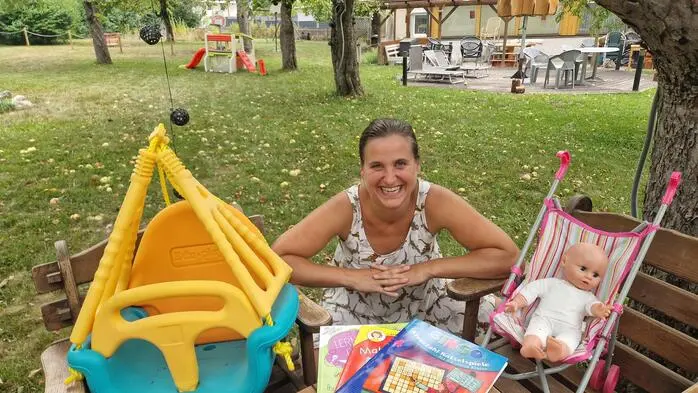Eine Frau in einem Garten umgeben von Spielsachen