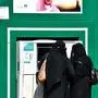 Saudi women withdraw money from an automatic teller machine along a main street in the capital Riyadh on December 18, 2018. (Photo by FAYEZ NURELDINE / AFP)