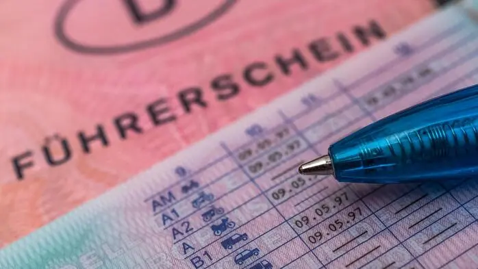 Man sieht den rosa Führerschein mit einem Kugelschreiber