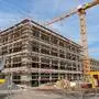 Eine Großbaustelle mit Baukran und Gebäuden im Rohbau | Die Auflagen bei Gewerbeimmobilien wurden strenger