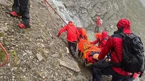 Mehrere Bergretter bergen eine verletzte Person aus steilem Gelände