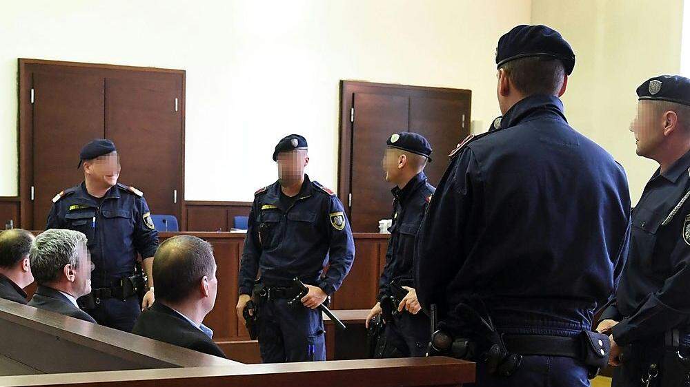 Die Angeklagten im Gerichtssaal unter strenger Aufsicht der Polizei