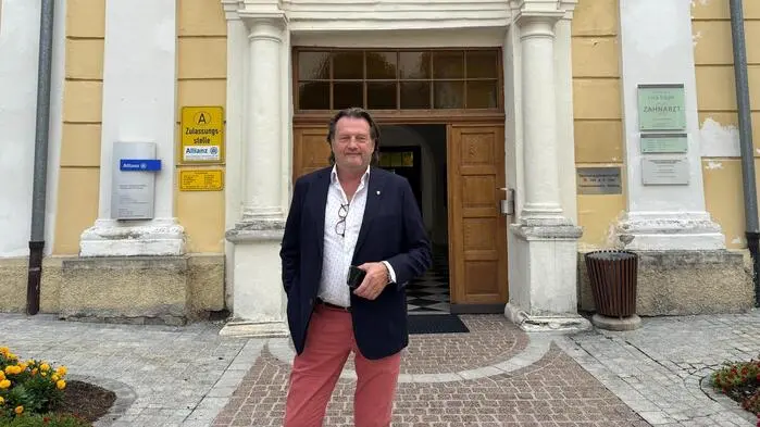 Ein Mann, Mitte 60, steht vor einem gelben Gebäude mit der Aufschrift „Stadtamt“.
