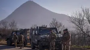 Italian soldiers serving in a NATO-led international peacekeeping mission in Kosovo patrol near a road barricaded with trucks by Serbs in the village of Rudare near the town of Zvecan on December 26, 2022. (Photo by Armend NIMANI / AFP)