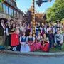 Eine größere Gruppe in Tracht steht um einen geschmückten Maibaum