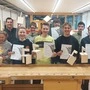 Die besten Tischlerinnen und Tischler im ersten Lehrjahr hinter einem Tischlertisch stehend