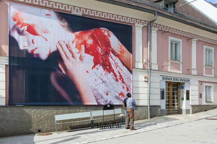 Die Ausstellung im Museum wird durch eine raumgreifende Installation Gottfried Helnweins am Bleiburger Hauptplatz ergänzt und erweitert – circa 10 Hausfassaden werden zu vom Künstler gestalteten großflächigen Bildträgern.