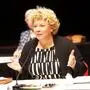 Eine Frau mit kurzen blonden Haaren vor einem Mikrofon