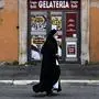 A nun walks past a closed ice-cream parlor on February 17, 2021 in central Rome. - Italy on February 12 extended a domestic travel ban and tightened restrictions in four regions amid rising concern about the spread of more infectious coronavirus variants. (Photo by Tiziana FABI / AFP)